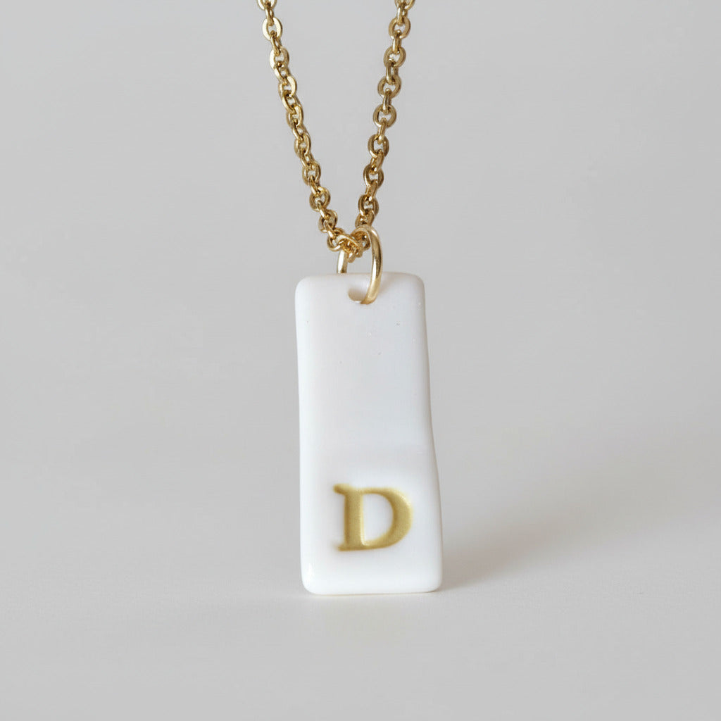 Gold Necklace with a white handmade porcelain pendant featuring a gold letter 'D'