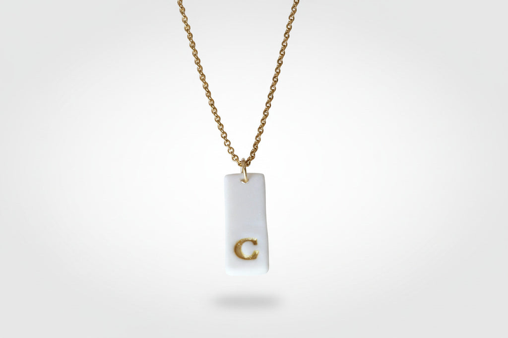 Gold Necklace with a white handmade porcelain pendant featuring a gold letter 'C'