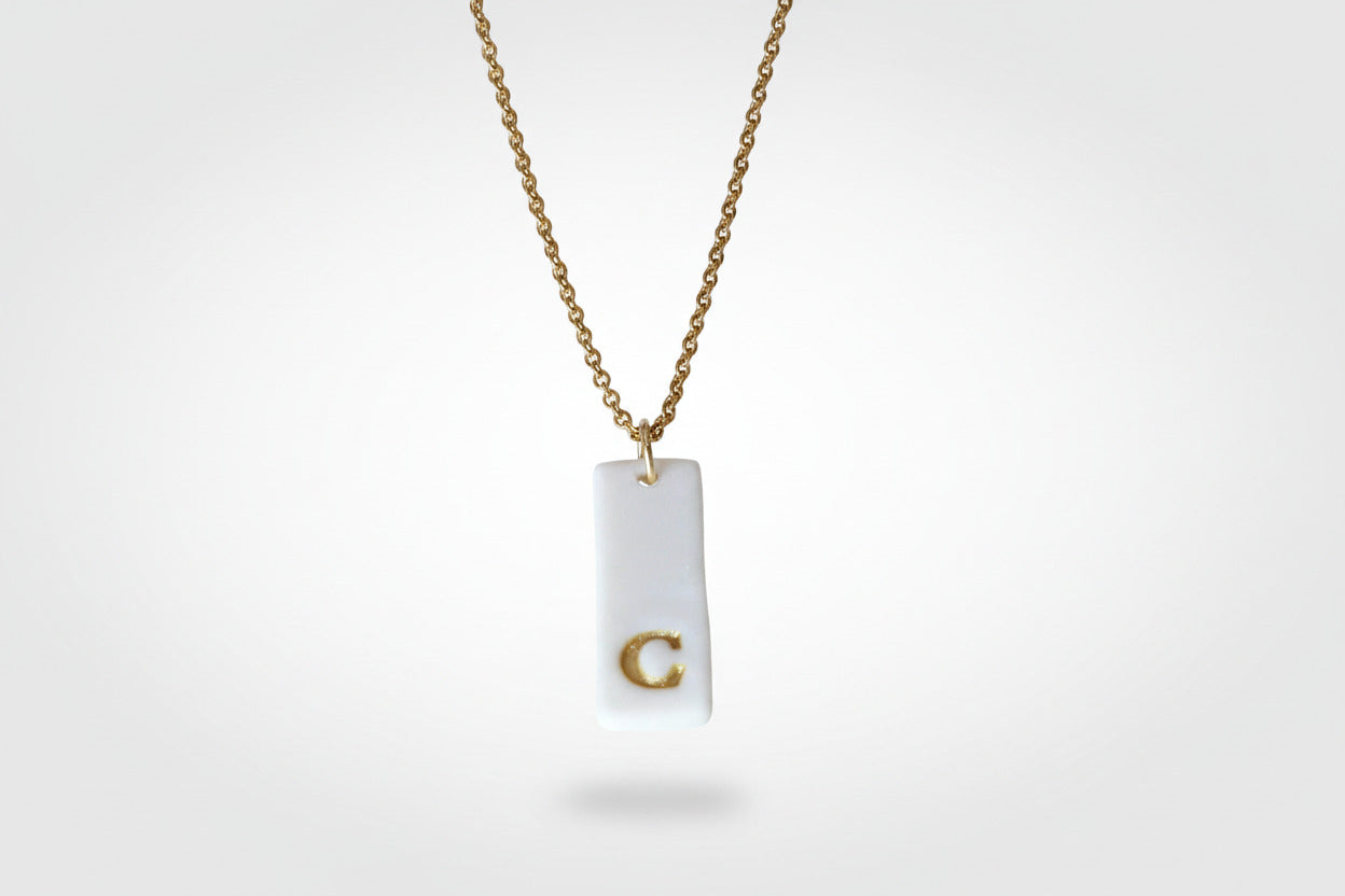 Gold Necklace with a white handmade porcelain pendant featuring a gold letter 'C'