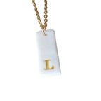 Gold Necklace with a white handmade porcelain pendant featuring a gold letter 'L'