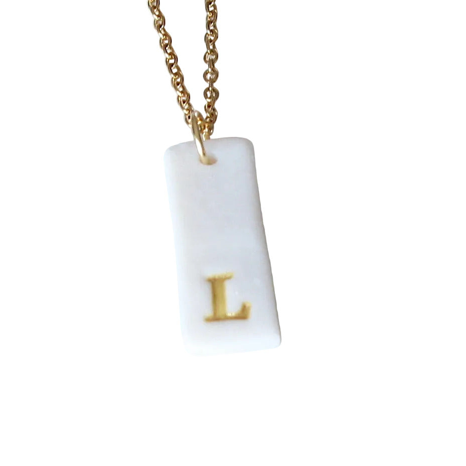 Gold Necklace with a white handmade porcelain pendant featuring a gold letter 'L'