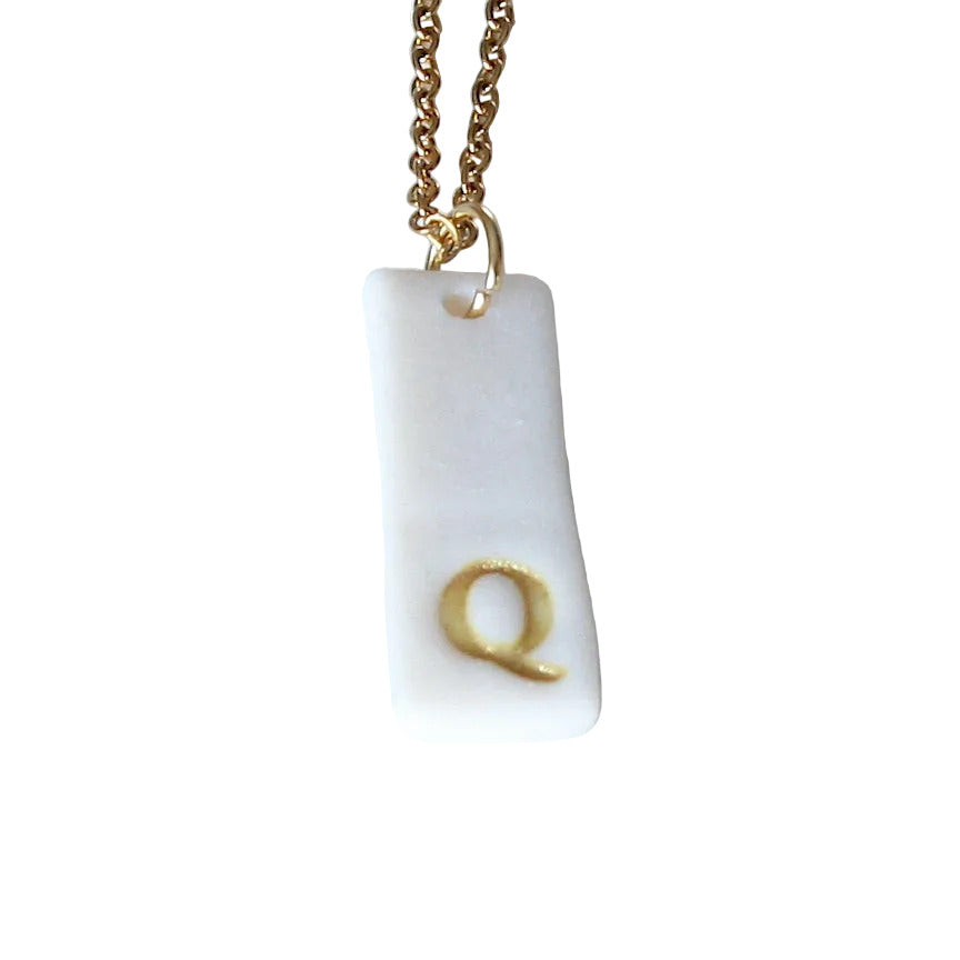 Gold Necklace with a white handmade porcelain pendant featuring a gold letter 'Q'