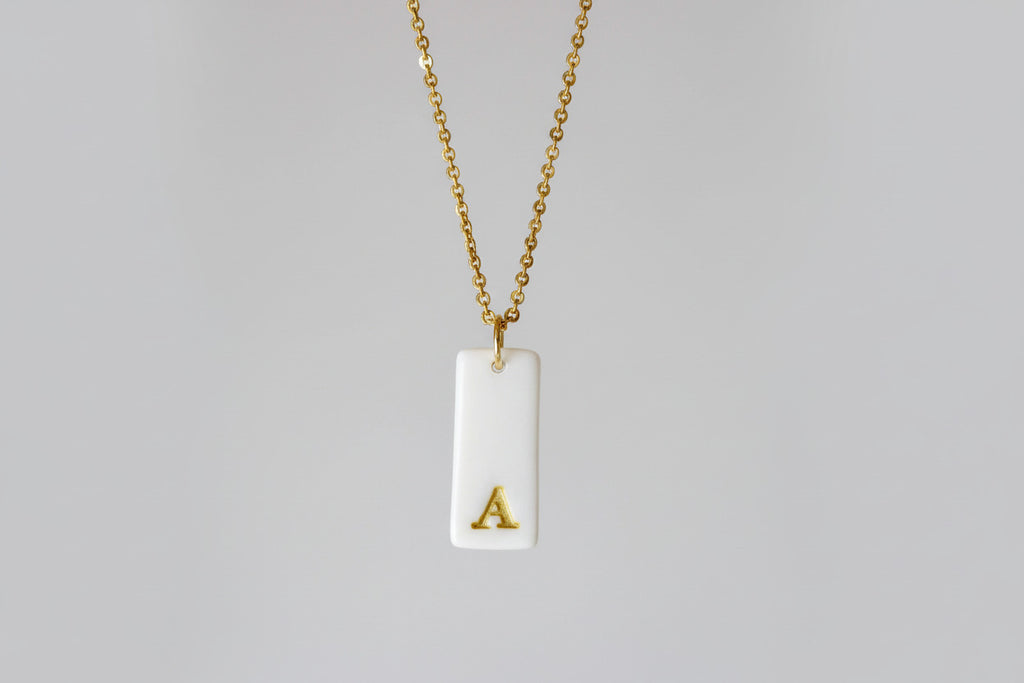 Gold Necklace with a white handmade porcelain pendant featuring a gold letter 'A'