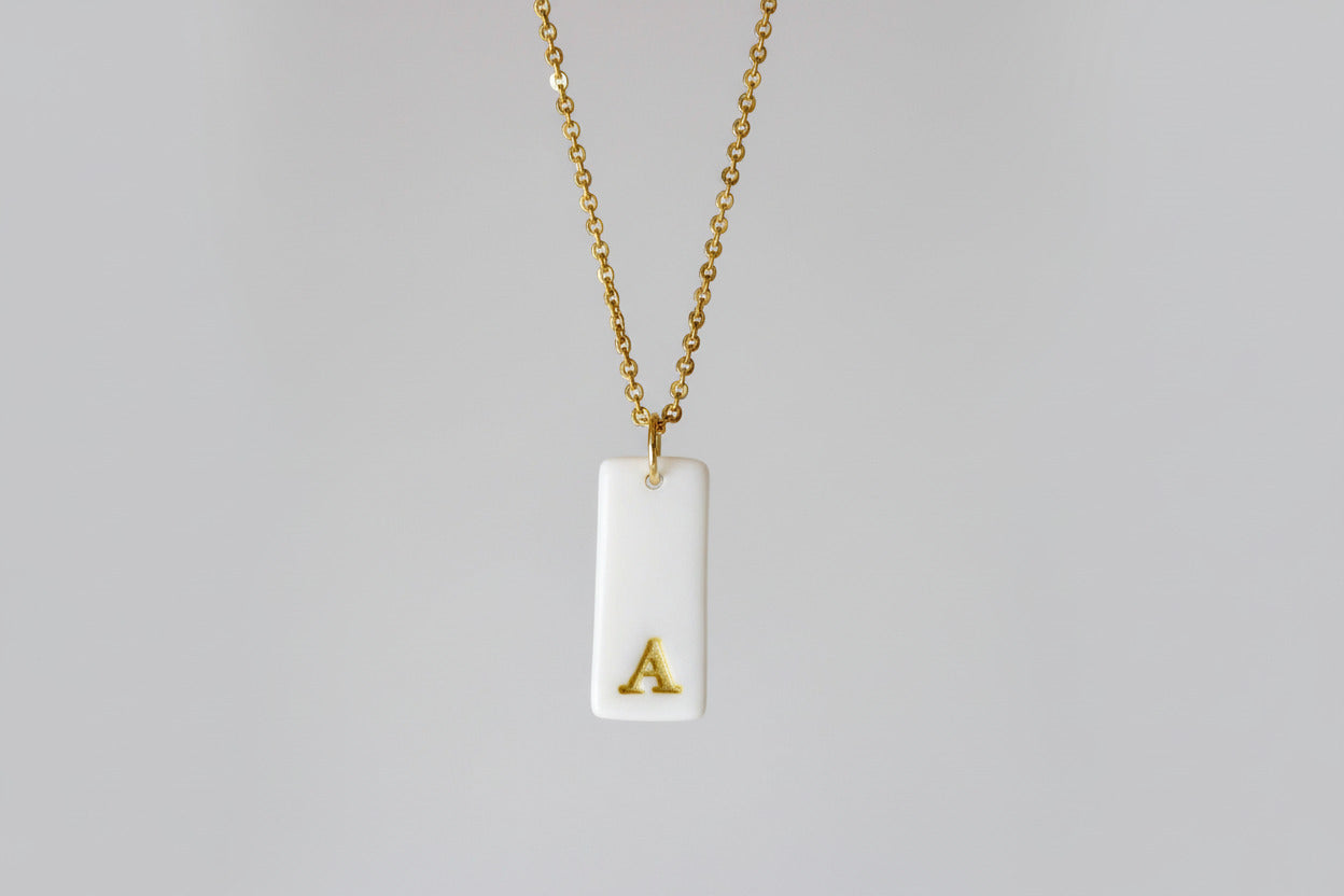 Gold Necklace with a white handmade porcelain pendant featuring a gold letter 'A'