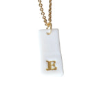 Gold Necklace with a white handmade porcelain pendant featuring a gold letter 'E'