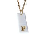 Gold Necklace with a white handmade porcelain pendant featuring a gold letter 'F'