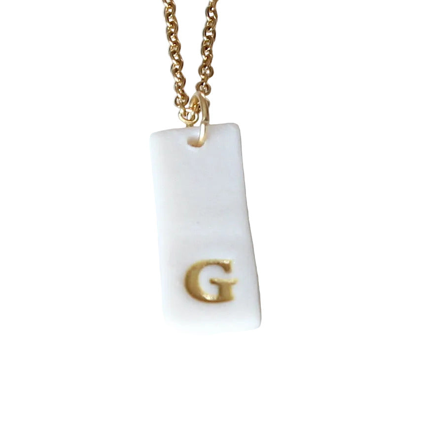 Gold Necklace with a white handmade porcelain pendant featuring a gold letter 'G'