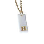 Gold Necklace with a white handmade porcelain pendant featuring a gold letter 'H'