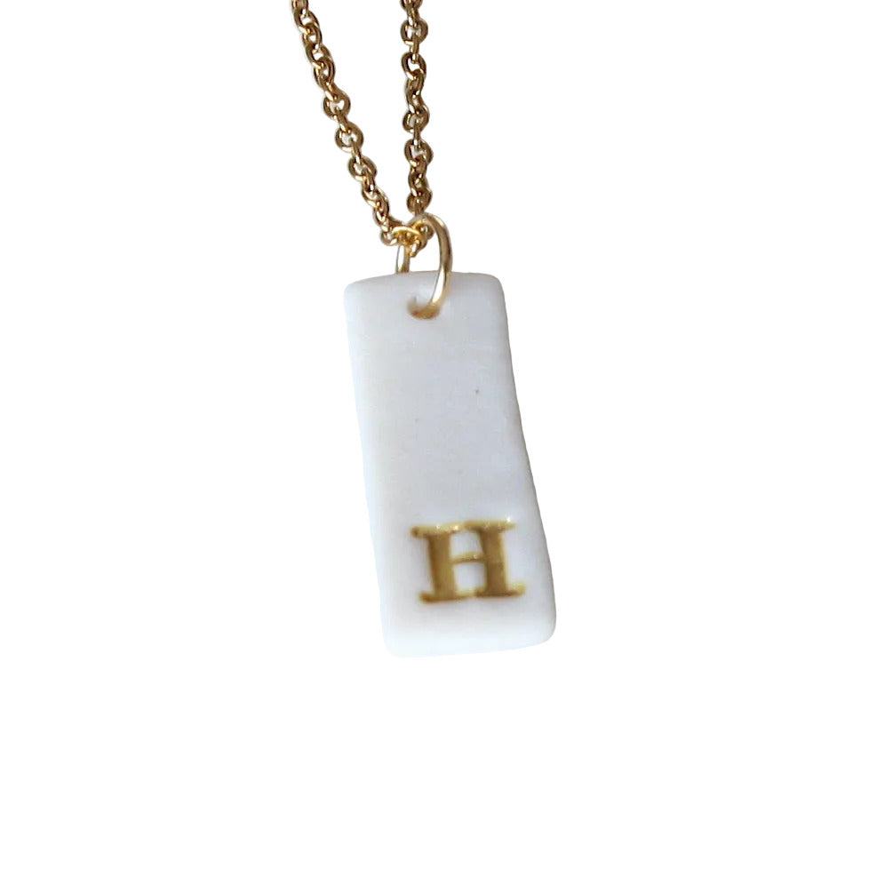 Gold Necklace with a white handmade porcelain pendant featuring a gold letter 'H'
