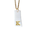 Gold Necklace with a white handmade porcelain pendant featuring a gold letter 'K'