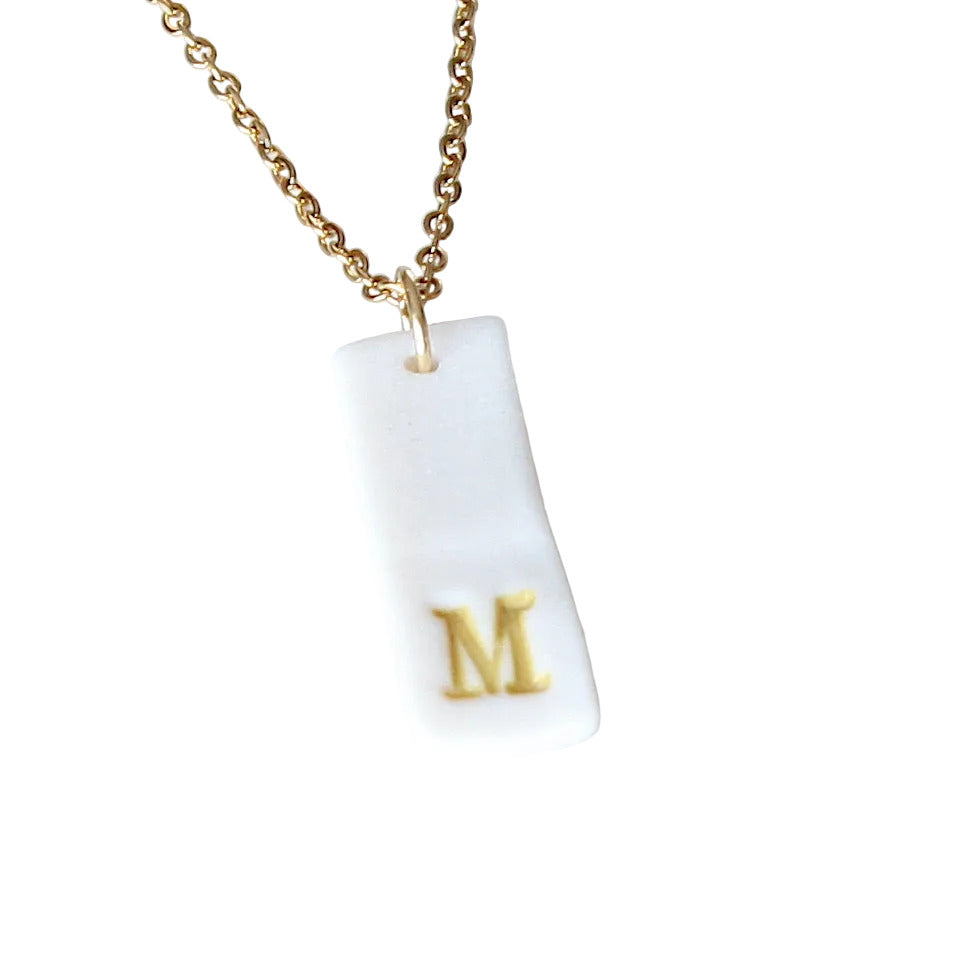 Gold Necklace with a white handmade porcelain pendant featuring a gold letter 'M'
