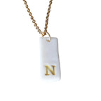 Gold Necklace with a white handmade porcelain pendant featuring a gold letter 'N'