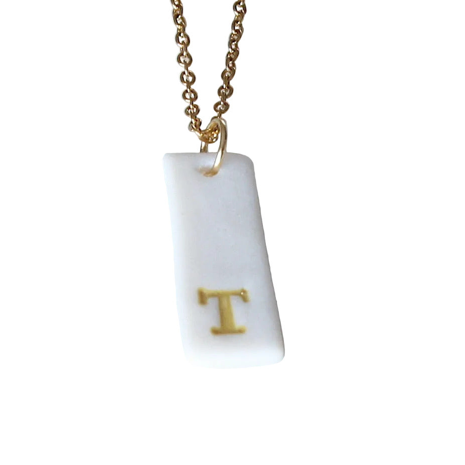 Gold Necklace with a white handmade porcelain pendant featuring a gold letter 'T'