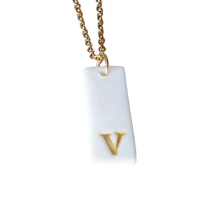 Gold Necklace with a white handmade porcelain pendant featuring a gold letter 'V'